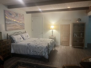 A bedroom with a bed, bedside table, lamp, bookshelf, and a painting on the wall. - Beautiful Private Forest Getaway in Peachtree Corners. (Peachtree Corners)