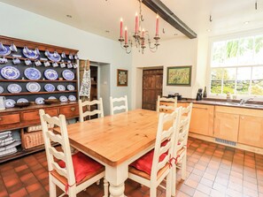 A dining area with a wooden table and chairs, a wall-mounted plate rack, and a chandelier. - Hart Head Farm (Ambleside)