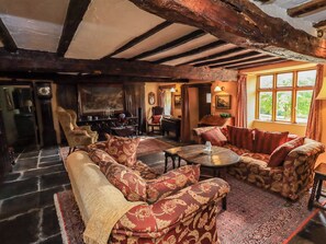 A traditional room with a fireplace, wooden beams, a sofa set, and a dining table. - Hart Head Farm (Ambleside)