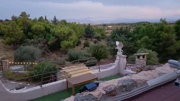 Eine Terrasse mit Steinbalustrade, einem Holztisch und einer Adlerstatue.