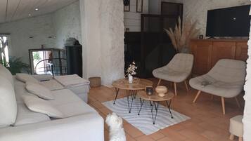 A cozy living room with a sofa, armchairs, a coffee table, and a television.