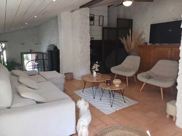 A cozy living room with a sofa, armchairs, a coffee table, and a television.