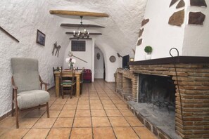 A rustic interior with a fireplace, a dining table, and a chair.