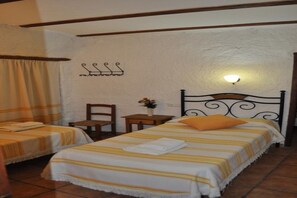 A room with two beds, a nightstand, a chair, and a wall-mounted light fixture.