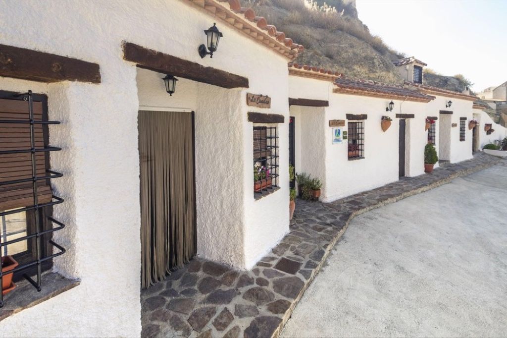A row of white buildings with stone foundations, wooden doors, and black window bars.