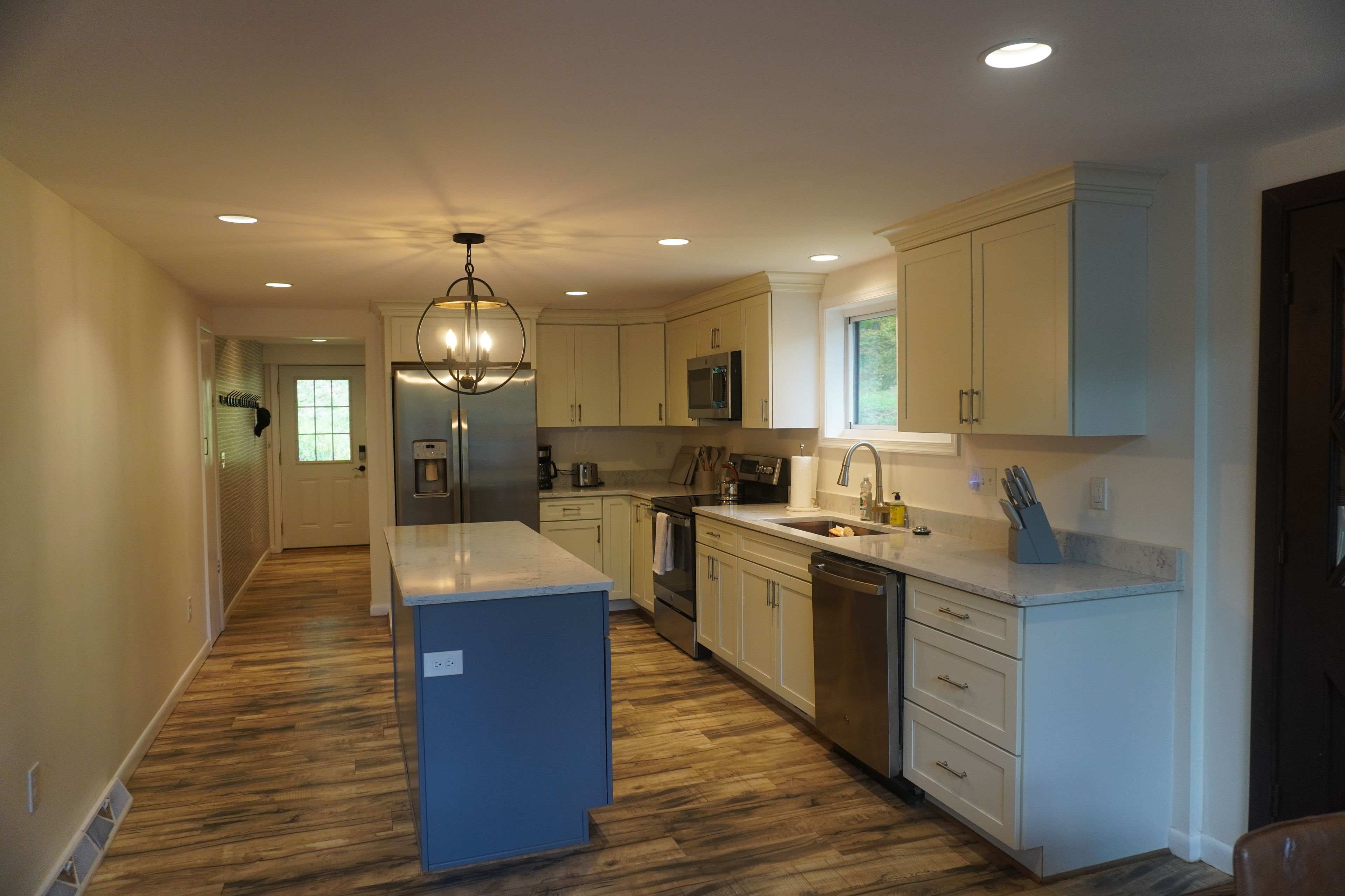 A modern kitchen with white cabinetry, a central island, and a stainless steel refrigerator.