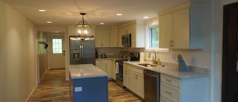 A modern kitchen with white cabinetry, a central island, and a stainless steel refrigerator.