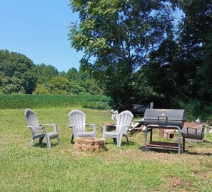 An outdoor setting with three Adirondack chairs, a grill, and a stone fireplace. - The Green House                                Statesville,NC (Statesville)