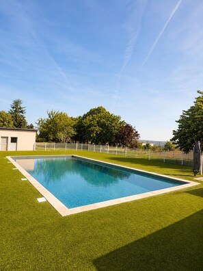 A rectangular swimming pool with a surrounding grassy area, a white fence, and trees in the background. - BELLEVUE VILLA, Pool - Air Conditioning - Panoramic View - Pets Welcome (Ayen)