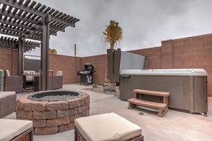 Eine Außenpatio-Terrasse mit Whirlpool, Sitzgelegenheiten und Grill.