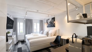 Et hotelværelse med seng, skrivebord, stol, tekøkken og et stort vindue.