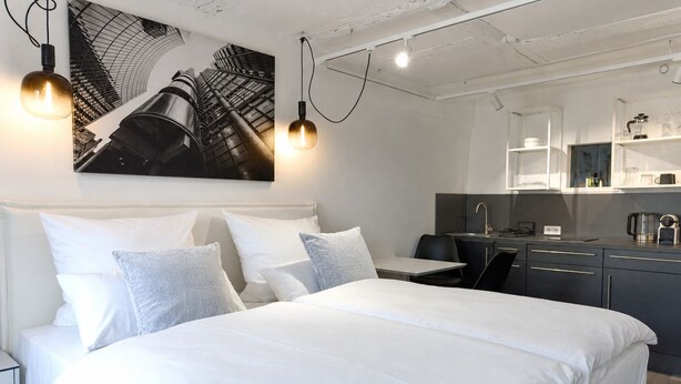 Et moderne hotelværelse med en stor seng, et skrivebord og et tekøkken.