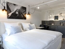 Una habitación de hotel moderna con una cama grande, un escritorio y una kitchenette.
