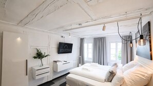 Et moderne hotelværelse med seng, sengeborde, et fjernsyn og udsigt til det fri.
