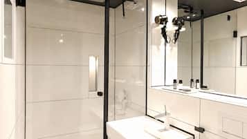 A modern bathroom with a large mirror, a white sink, and a shower area.