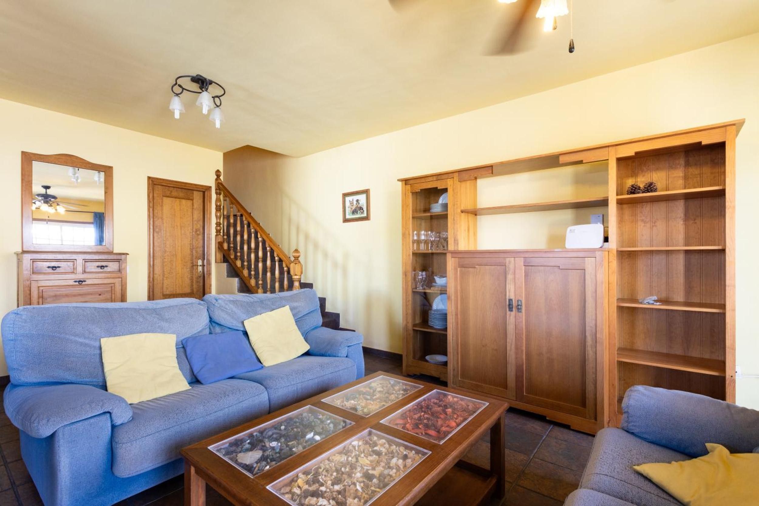 Una sala de estar con un sofá azul, un armario de madera y una escalera.