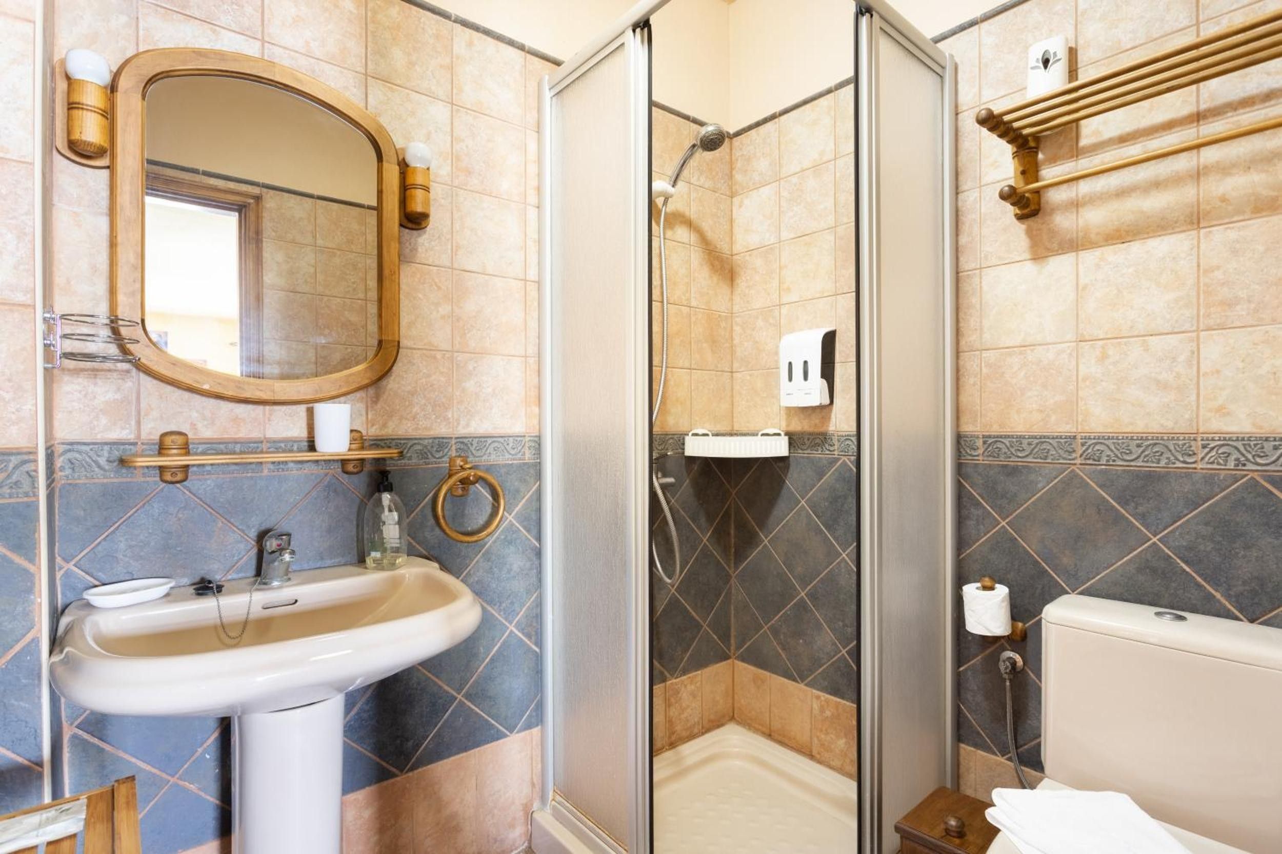 Un baño con lavabo, espejo, ducha, inodoro y toallero.