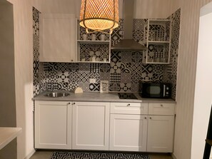 Una cucina con piastrelle decorate, un forno a microonde, un lavello e un lampadario.