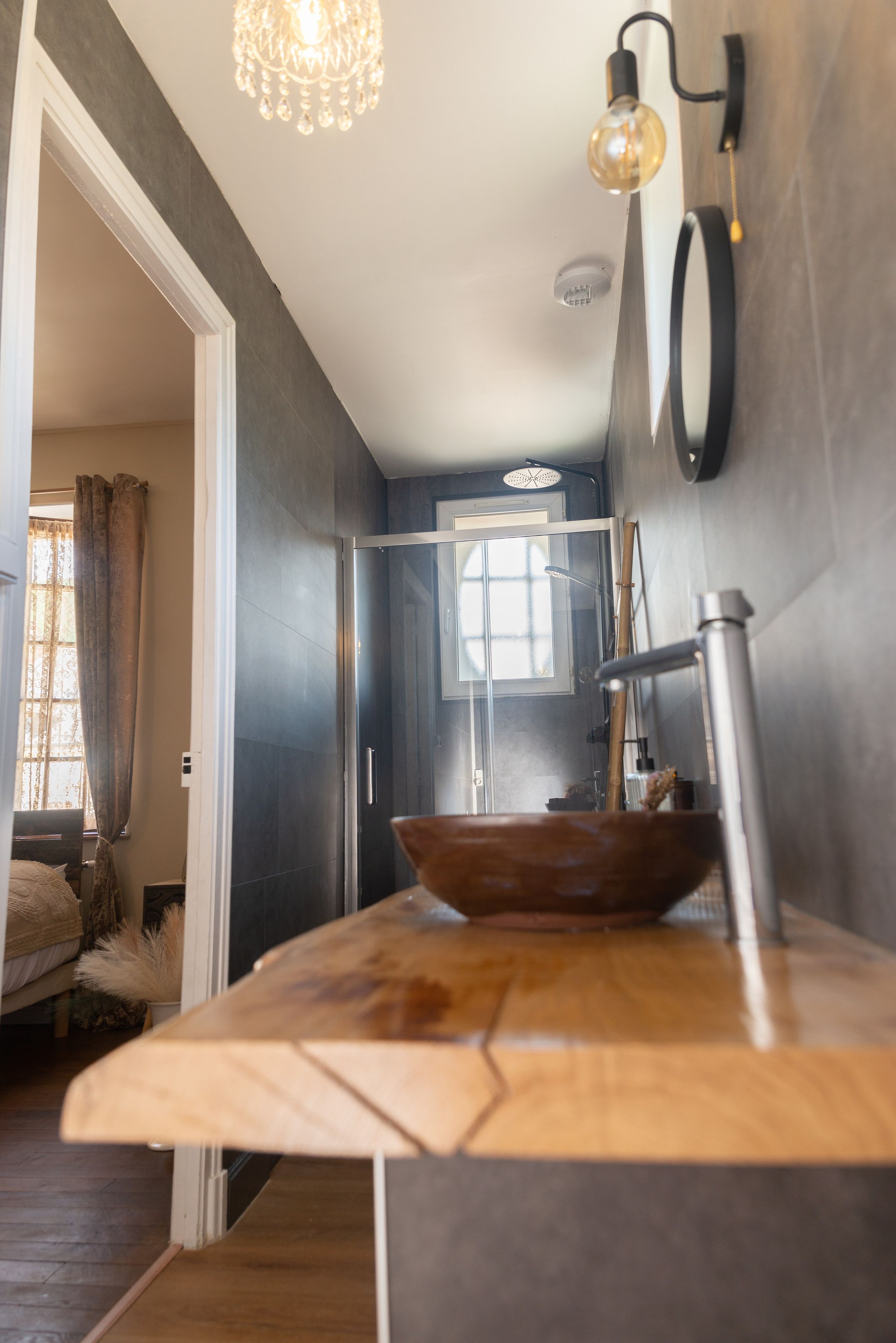 Una cocina moderna con encimera de madera, una lámpara colgante y una ventana con cortinas.