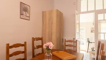 Een eetgedeelte met een houten tafel, stoelen, een vaas met bloemen en een houten kast.