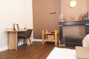 Una sala de estar acogedora con un escritorio de madera, un sillón cómodo, una chimenea con adornos decorativos y una alfombra mullida.