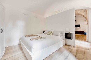 Una camera da letto con un letto grande, un comodino con una lampada e una TV montata a parete.