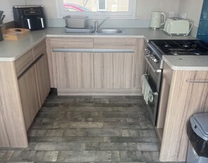 Eine kompakte Küche mit Backofen, Kochfeld und Spüle.