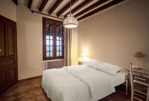 Une chambre à coucher avec un lit, une fenêtre, un radiateur et une table de chevet avec une lampe.