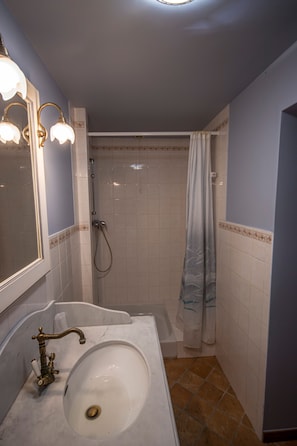 Une salle de bain avec un lavabo blanc, une douche et une baignoire.
