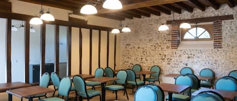 Un comedor con mesas y sillas de madera, paredes de piedra e iluminación colgante.