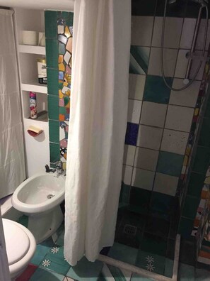 Ein Badezimmer mit Dusche, Toilette und einem Ablagefach für Toilettenartikel.