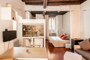 Un espace de vie compact comprenant une kitchenette, un coin repas et une chambre.