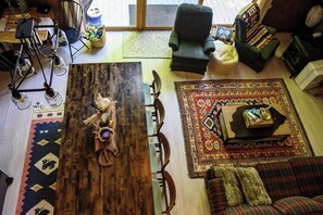 A cozy living room with a wooden coffee table, a sofa, and a chair. There is a rug on the floor and a window in the background.