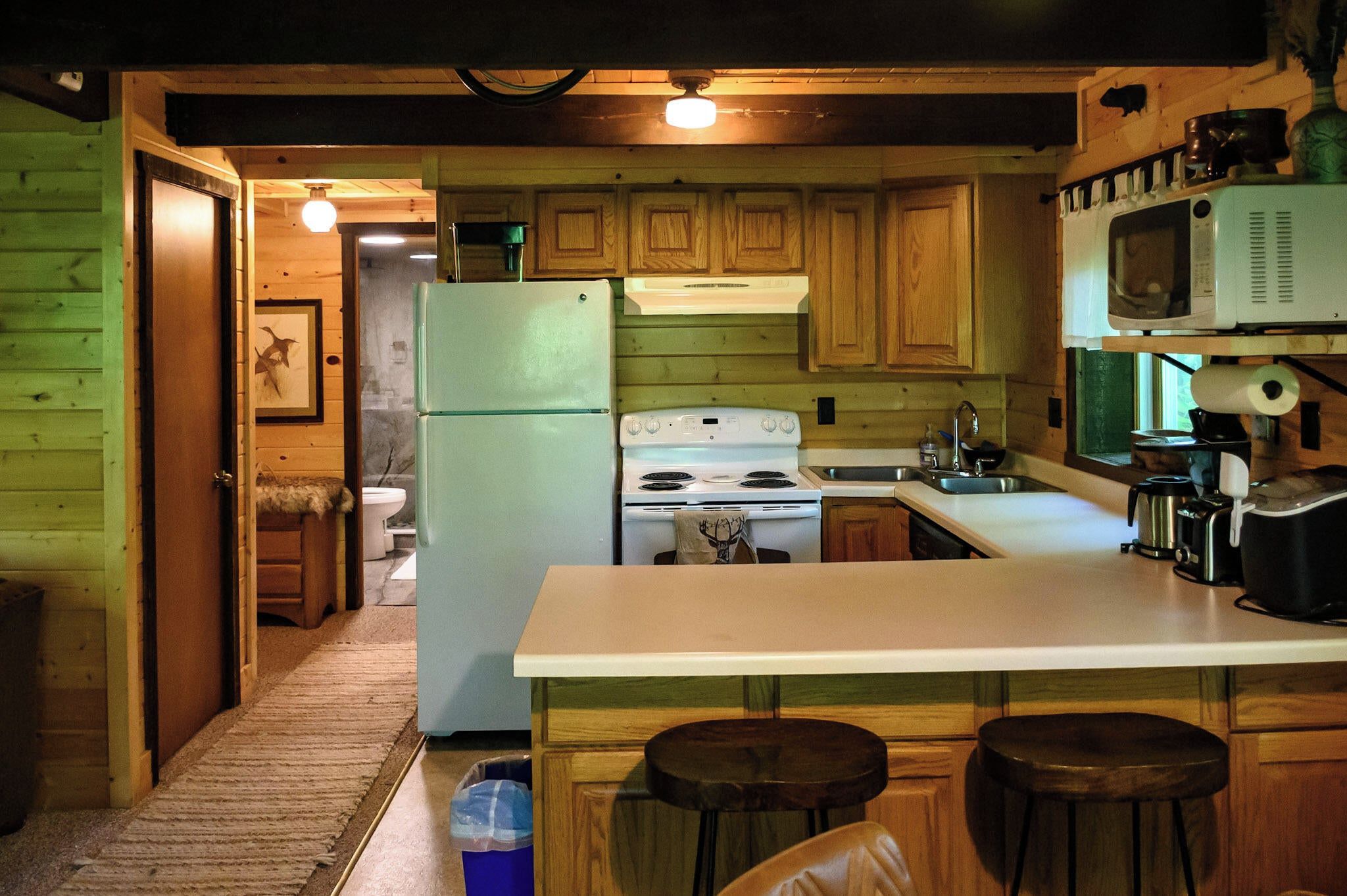 A kitchen with wooden cabinets, a refrigerator, a stove, a microwave, and a sink.