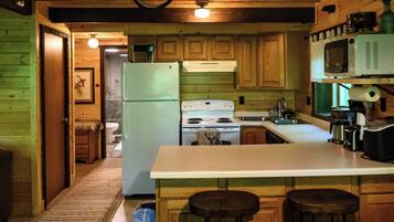 A kitchen with wooden cabinets, a refrigerator, a stove, a microwave, and a sink.