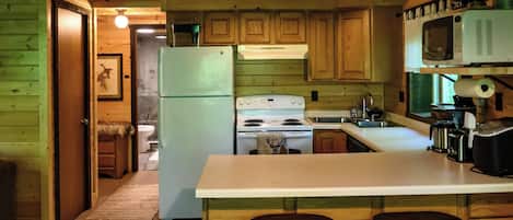 A kitchen with wooden cabinets, a refrigerator, a stove, a microwave, and a sink.