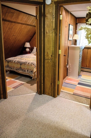 A room with a bed, a dresser, and a door leading to another room.