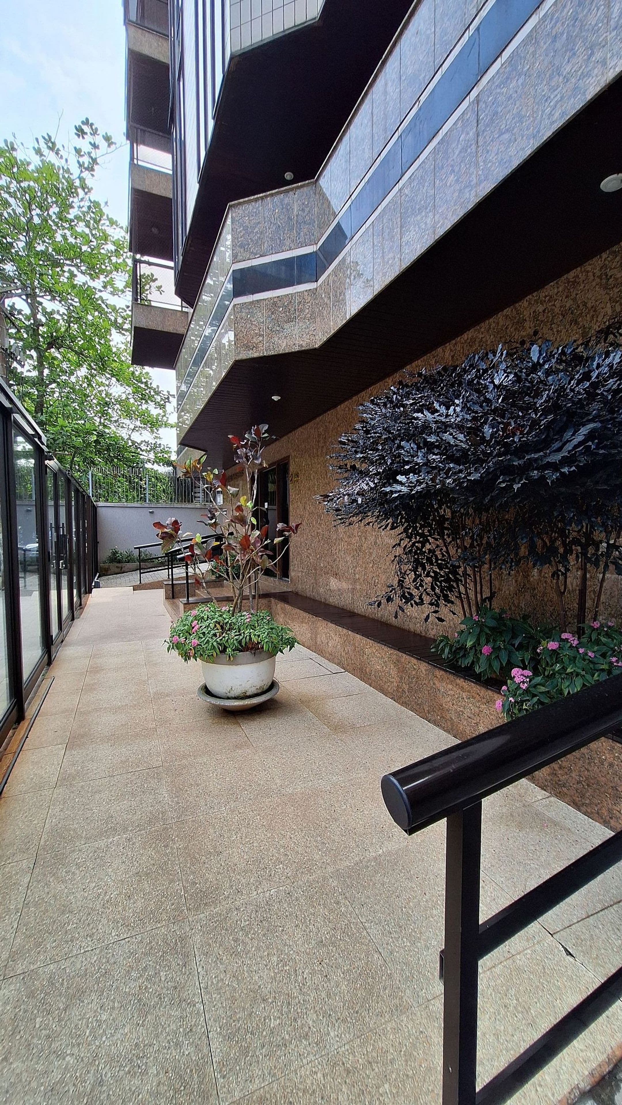 A modern building with a glass facade, outdoor seating area, and potted plants.