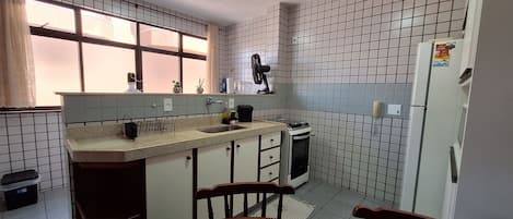 A compact kitchen with a window, a stove, and a refrigerator.