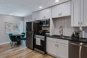 A modern kitchen with white cabinets, stainless steel appliances, and a black countertop. - Shepard`s Lodge - families and pets welcome! (Indianapolis)