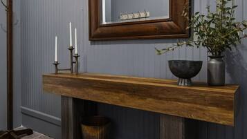 Une pièce comprenant une console en bois, un miroir, une plante et un chandelier.
