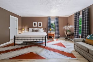 Un dormitorio con cama, escritorio y sofá.