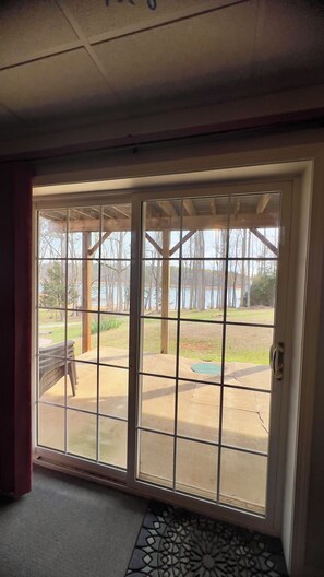 A view through a glass door with a metal grid, leading to an outdoor patio area with a concrete floor and a wooden deck. - Lake Hartwell  Anderson/Townville SC with private dock! Close to Clemson (Townville)