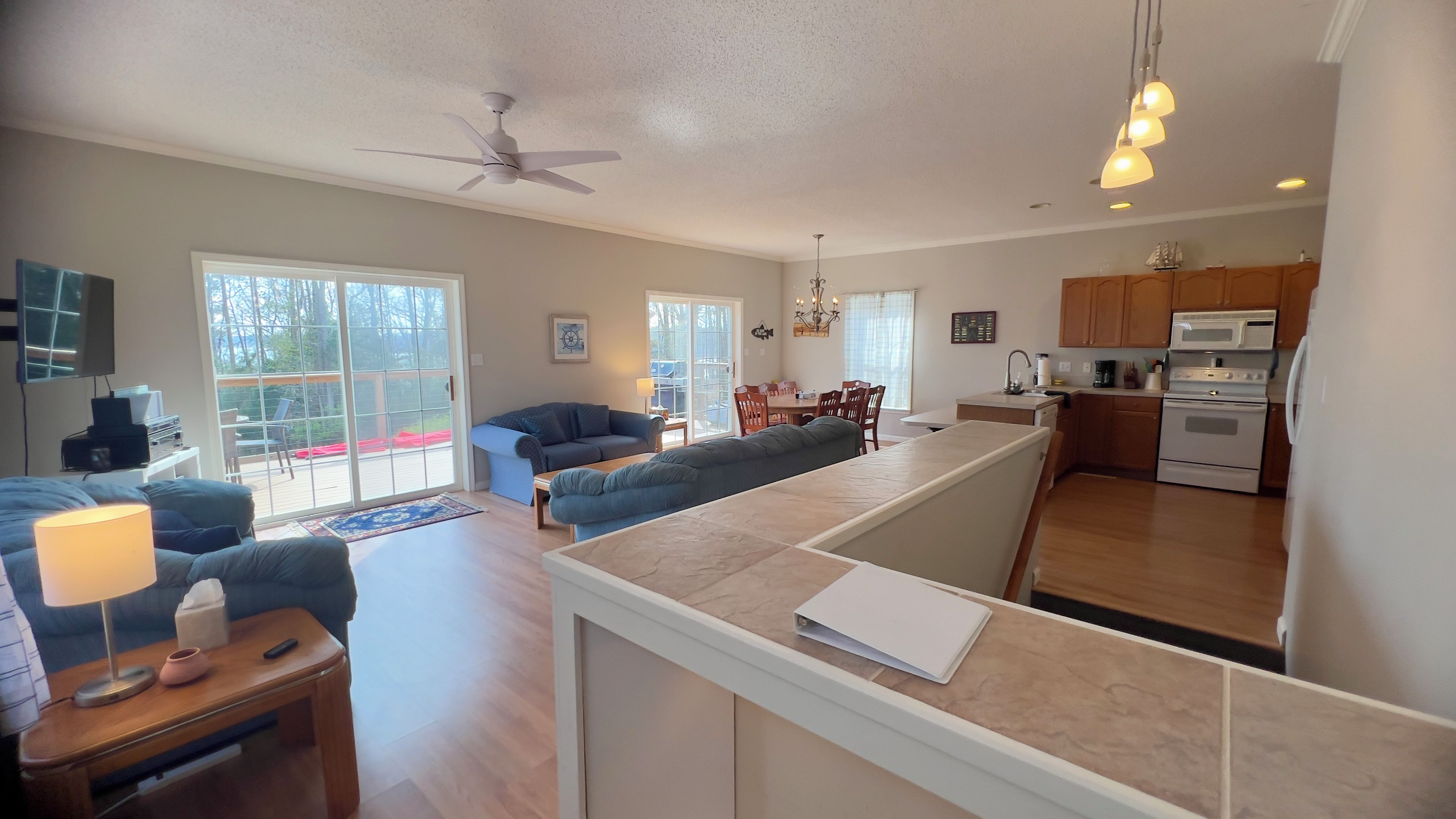 A spacious living area with a sofa, a coffee table, and a TV. There is a kitchen with modern appliances and wooden cabinets.
