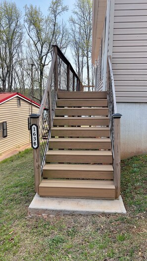 A wooden staircase with a metal railing leading to a house with a beige siding exterior. - Lake Hartwell  Anderson/Townville SC with private dock! Close to Clemson (Townville)