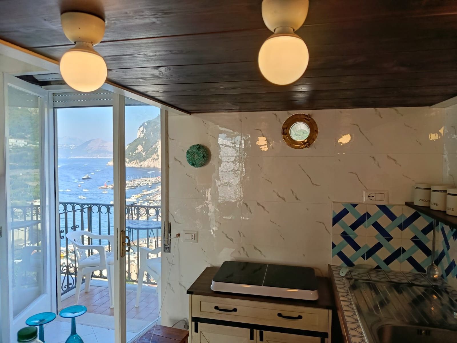 Una habitación con vista al mar, techo de madera, un armario blanco y salpicadero de azulejos.
