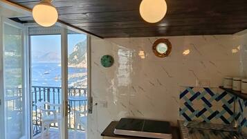 Una habitación con vista al mar, techo de madera, un armario blanco y salpicadero de azulejos.