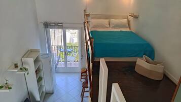 Un dormitorio con cama, balcón y vistas al exterior.