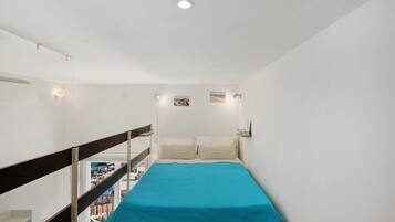 Ein schmales Zimmer mit Bett, Meerblick und einem Balkon.
