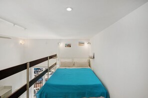 Una habitación pequeña con cama, vista al mar y balcón.